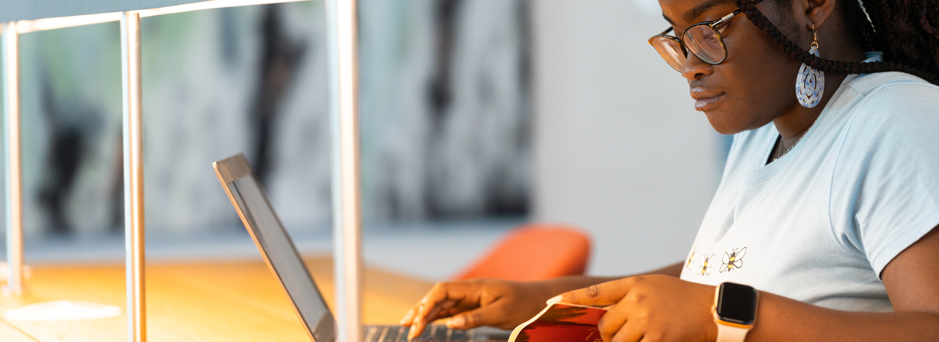 Girl reading a book and using a laptop