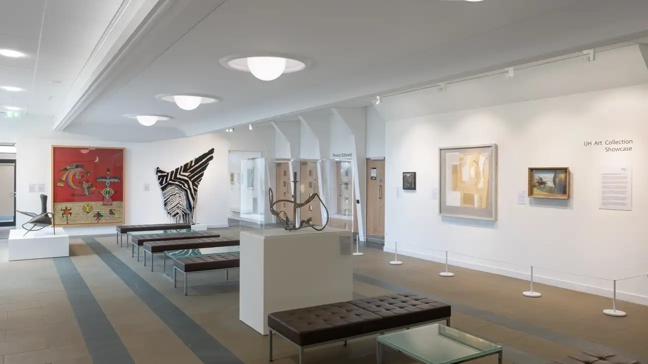 Art work on a wall and benches down the middle of the room