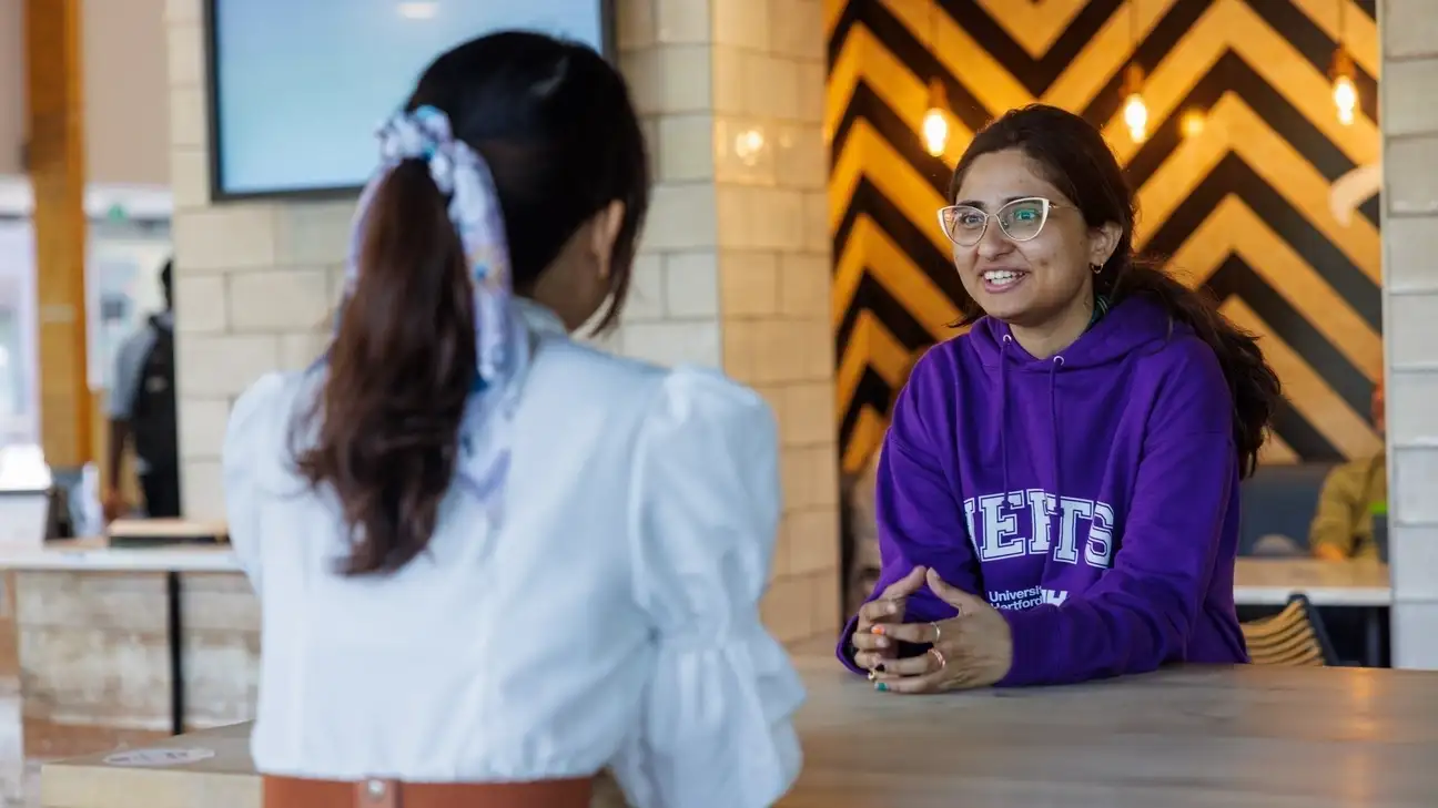 Two students sitting down at a table talking
