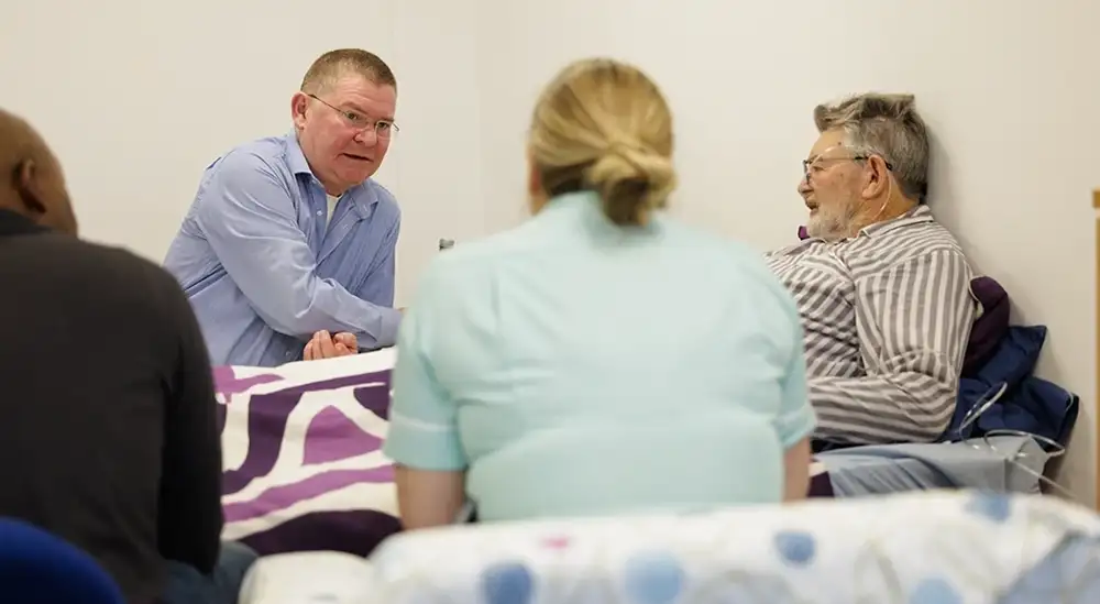 A student and lecturer practicing bedside manner with a patent in bed