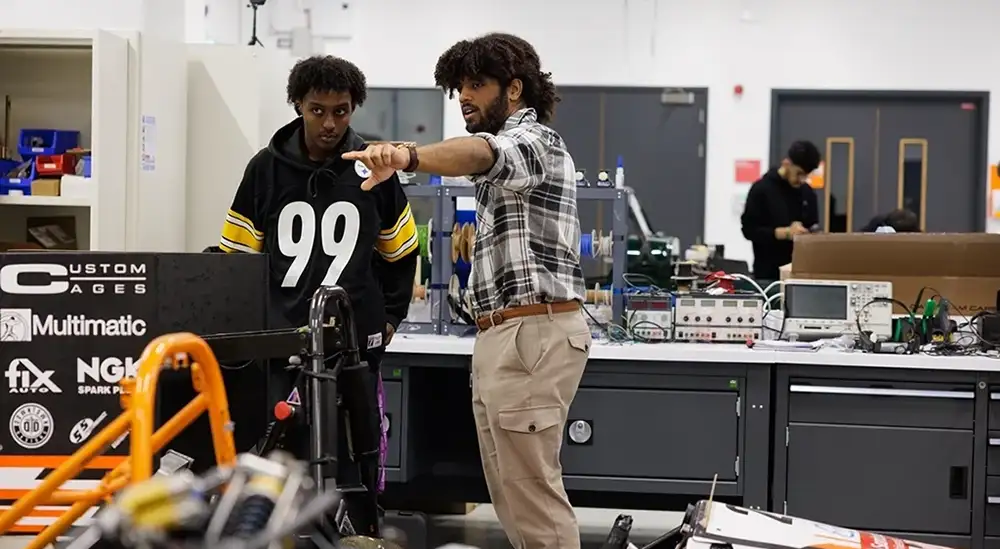 A lecturer pointing at somehitng in the distance to a student