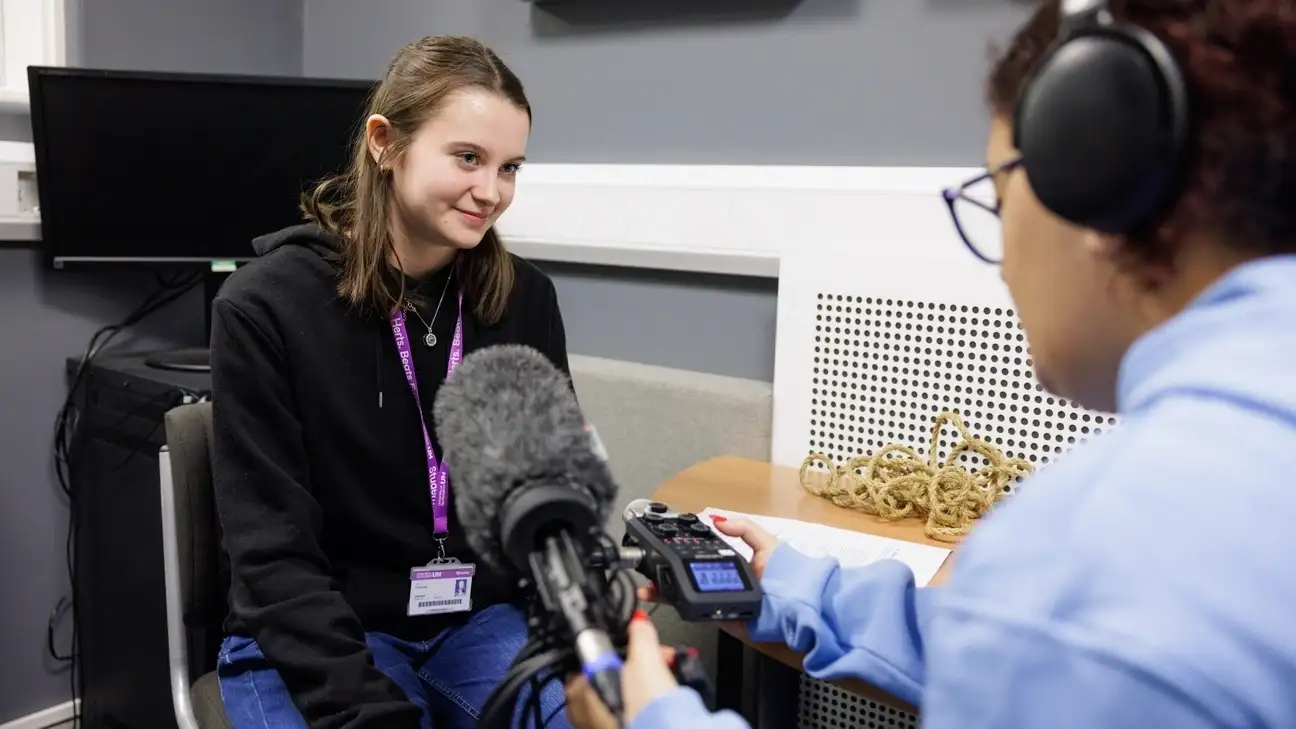 A student recording sounds with a microphone being help to them 