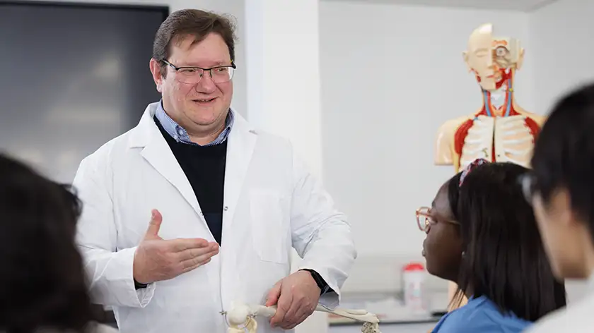 Lecturer in a lab coat talking to students