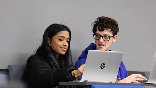 Two students looking at a laptop