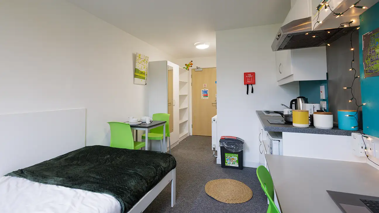 Waredrobe, bed, kitchen and desk with laptop