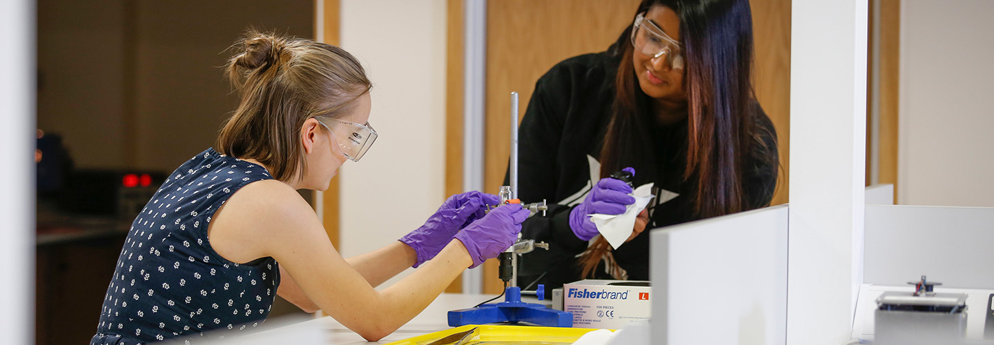 Two female physics students conduction an experiment