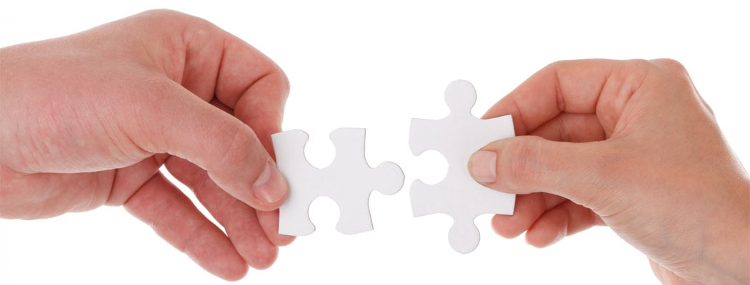 Two hands putting together jigsaw puzzle pieces