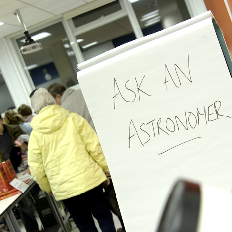 A person walks past a sign which reads 'ask an astronomer'