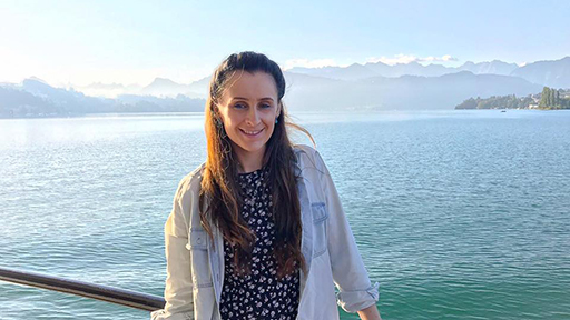 Anna stands in front of a blue sea on a sunny day