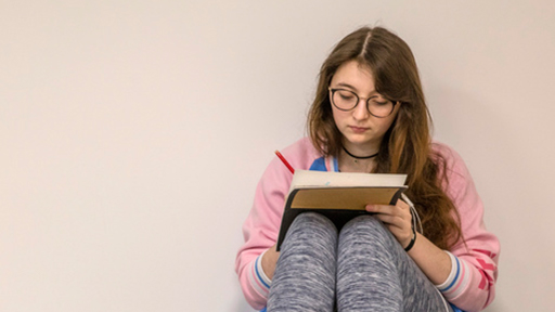 a writes on a notepad which rests on her knees