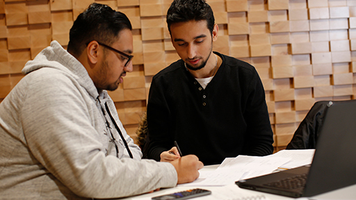 Two students sit with a laptop and calculator