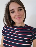 A picture of Nuala. She has short, brown hair and brown eyes. She is wearing a navy t-shirt with red and white stripes. The background is white.