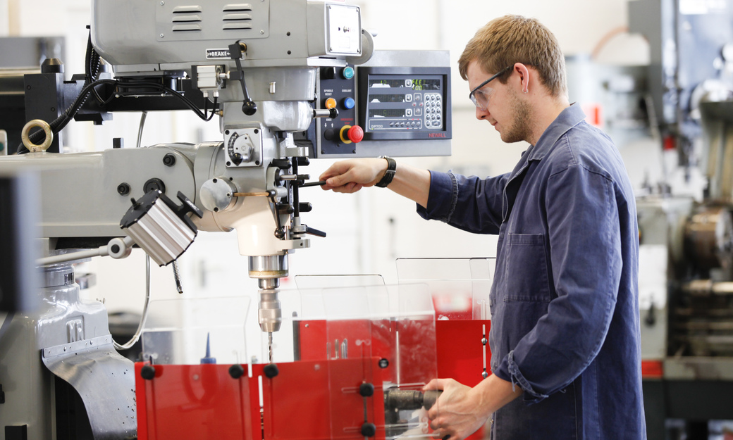 A student working one of the drill press machines in the workshop