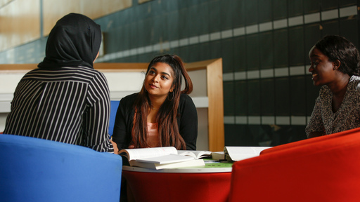 Three diverse female students sitting down having a conversation