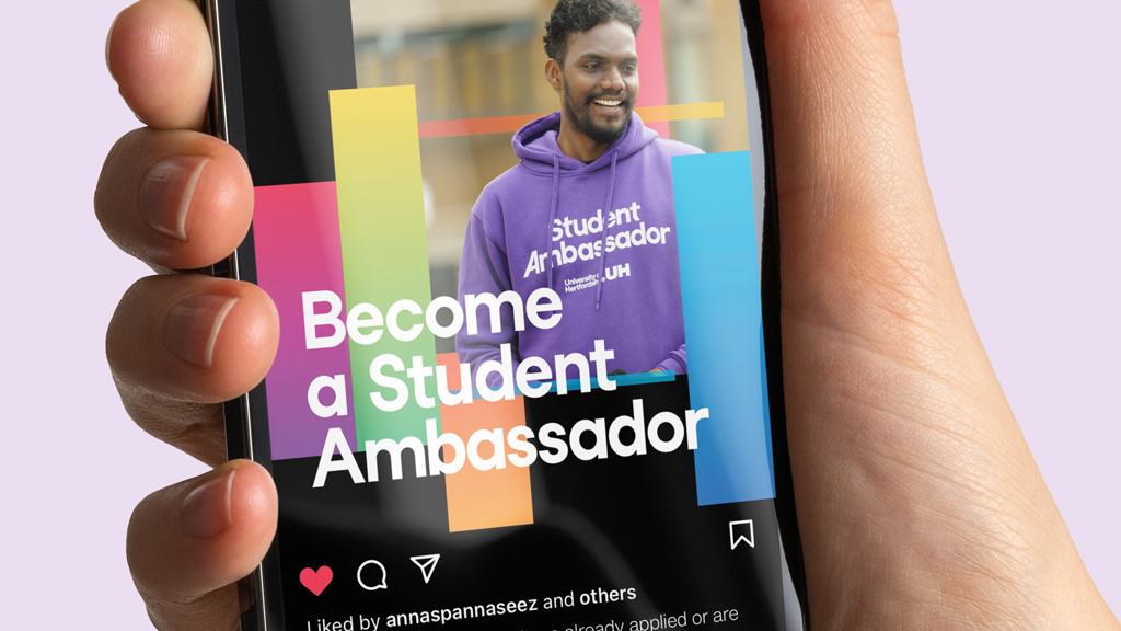 hand holding an iPhone, displaying a social media post by the university of hertfordshire