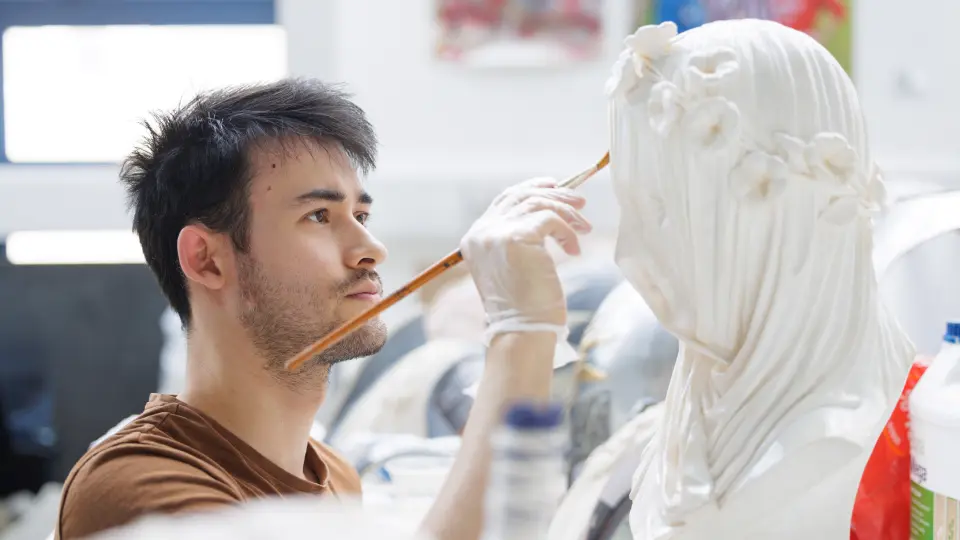 Male student painting a sculpture 