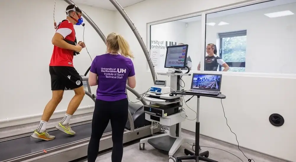 Stevenage players on a treadmill with a student suppoting