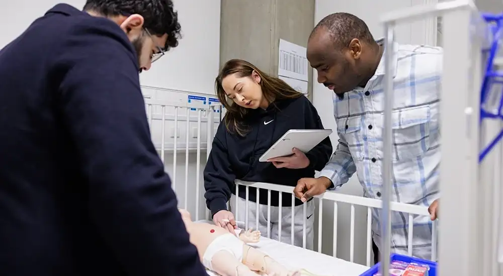 A student with lecturer practicing overlooking a cot