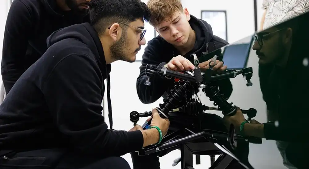 A group of students working on the suspension of a car