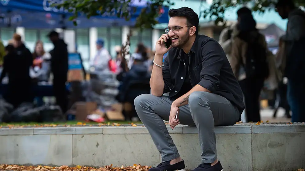 A student sitting down on a mobile phone