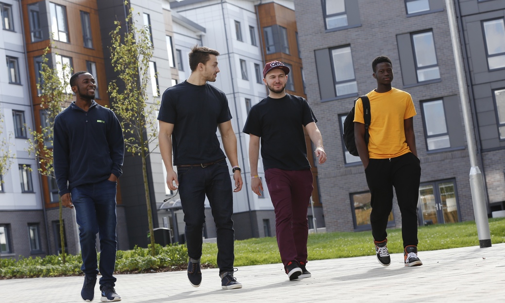 Four male students walking through campus