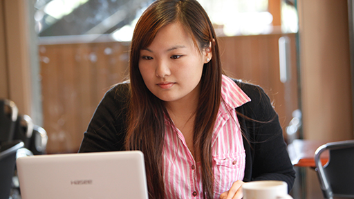 a student sits in a cafe looking at her laptop