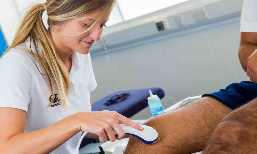 a student using an ultrasound machine on another student's knee