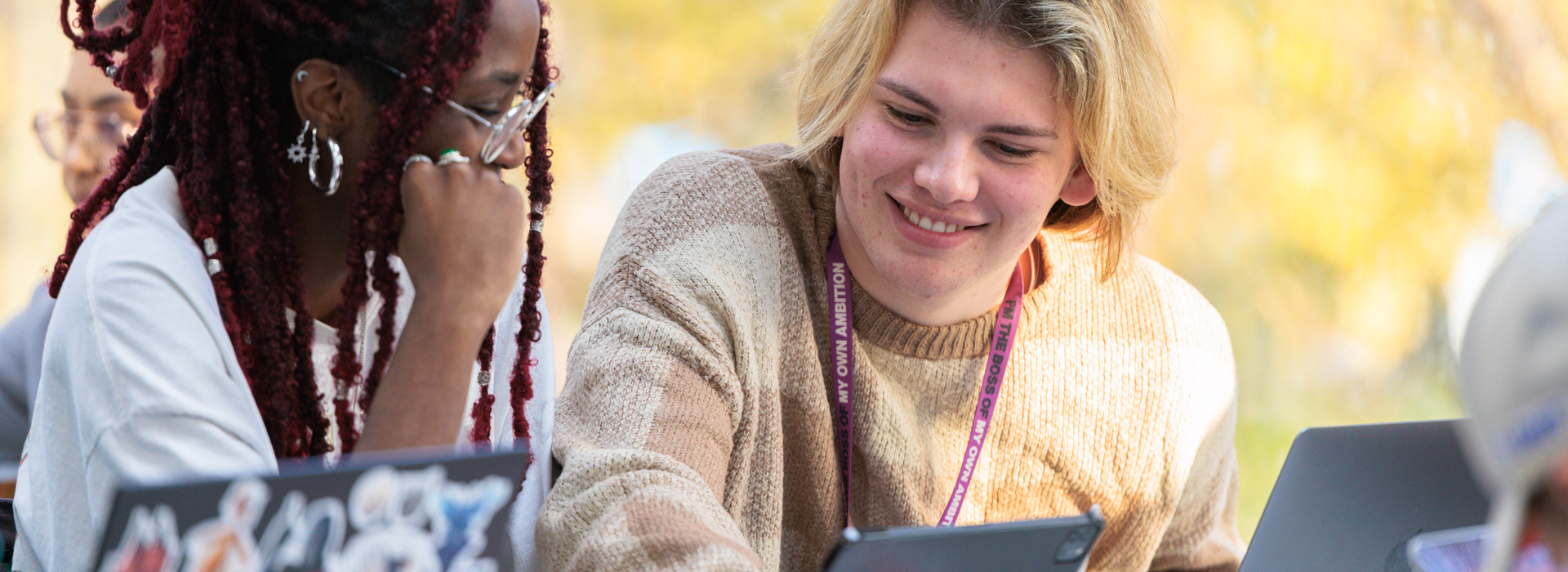 Smiling students, looking at a tablet, working