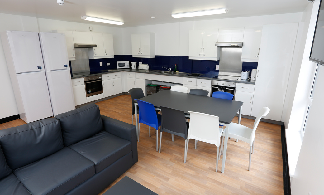 Accommodation communal kitchen showing cooking space, table, chairs and sofa