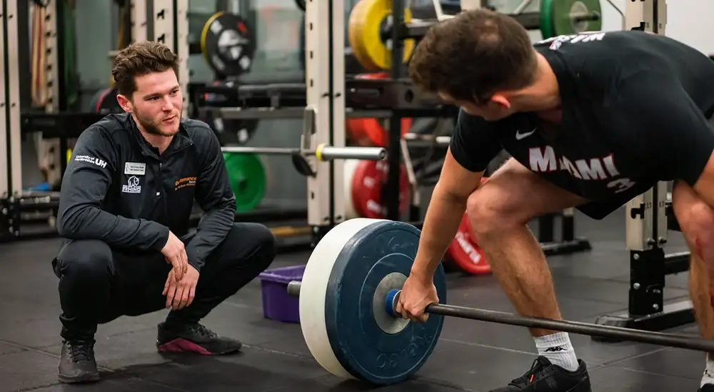 Person guiding someone on how to lift weight