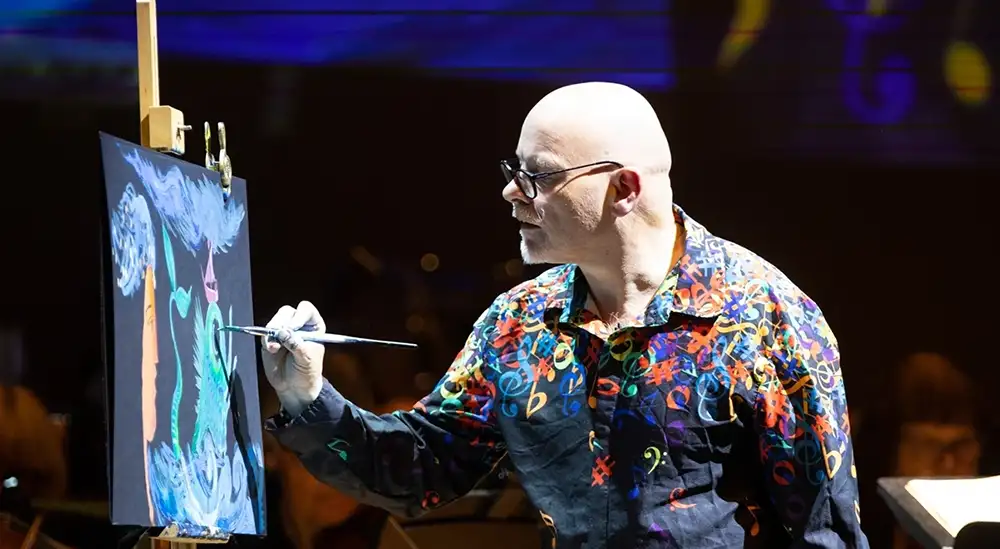 James Mayhew painting an image on a canvas 