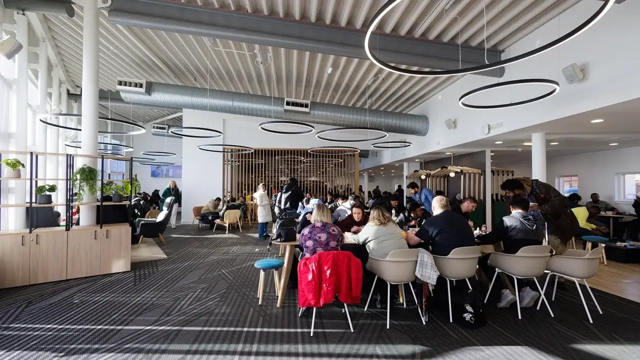 A large group of people sitting down in the food court