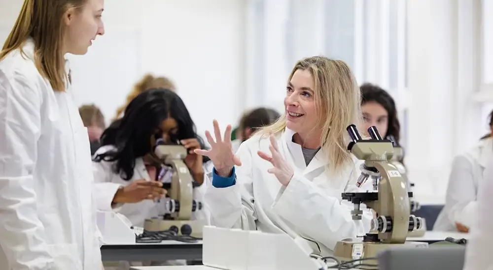 A lecturer in a lab coat explaining to a student