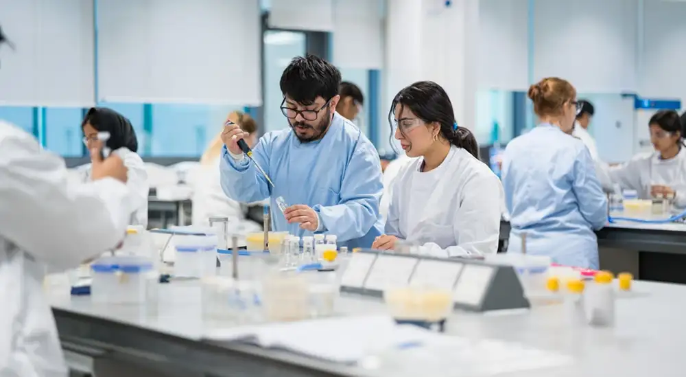Two students in a lab working with a pipet