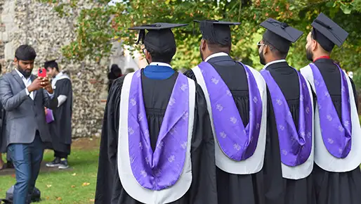 students at graduation with robes on taking a picture