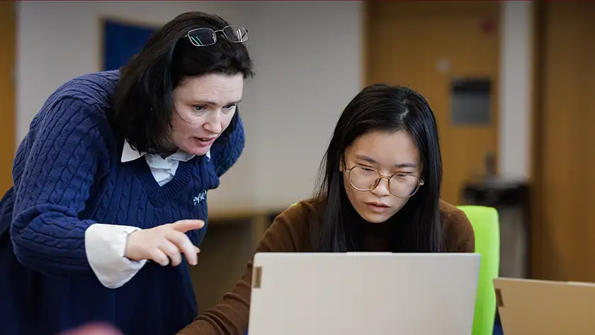 Support staff helping a student on a laptop