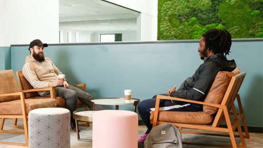 Two male students talking on chairs with coffee