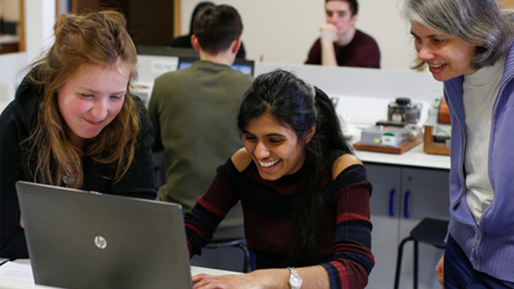 Two female students at laptop with academic