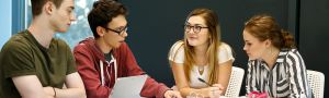 four students have a discussion around a table