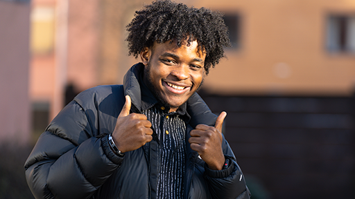 Student smiling at camera with thumbs up