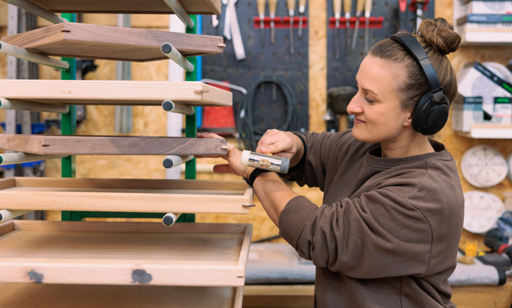 MOnikia using a hammer to finish creating a wooden tray