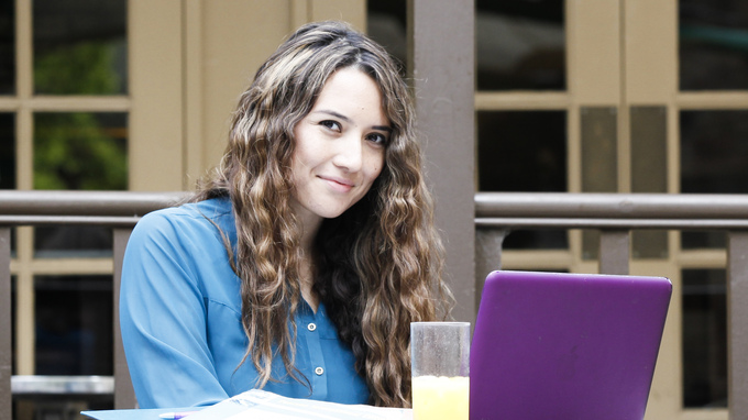 Image of a female sitting at an outside table with laptop