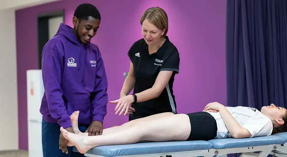 A student practicing on the ankle of another student with lecturer
