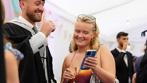 Student at graduation looking at phone 
