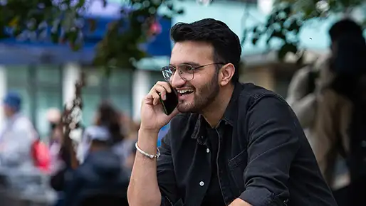 A student sitting down on a mobile phone