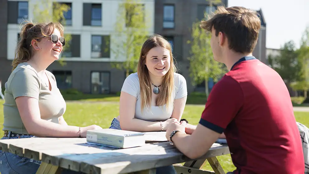 Students sitting round a table outside