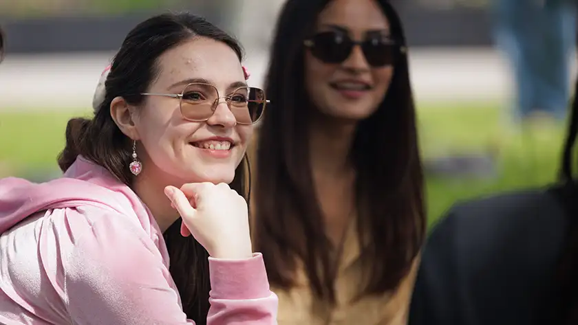 Student wearing sunglasses outside smiling