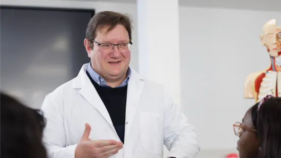 Person in lab coat giving lecture 