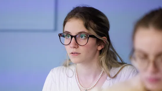 A student wearing glasses listening in a lecture 