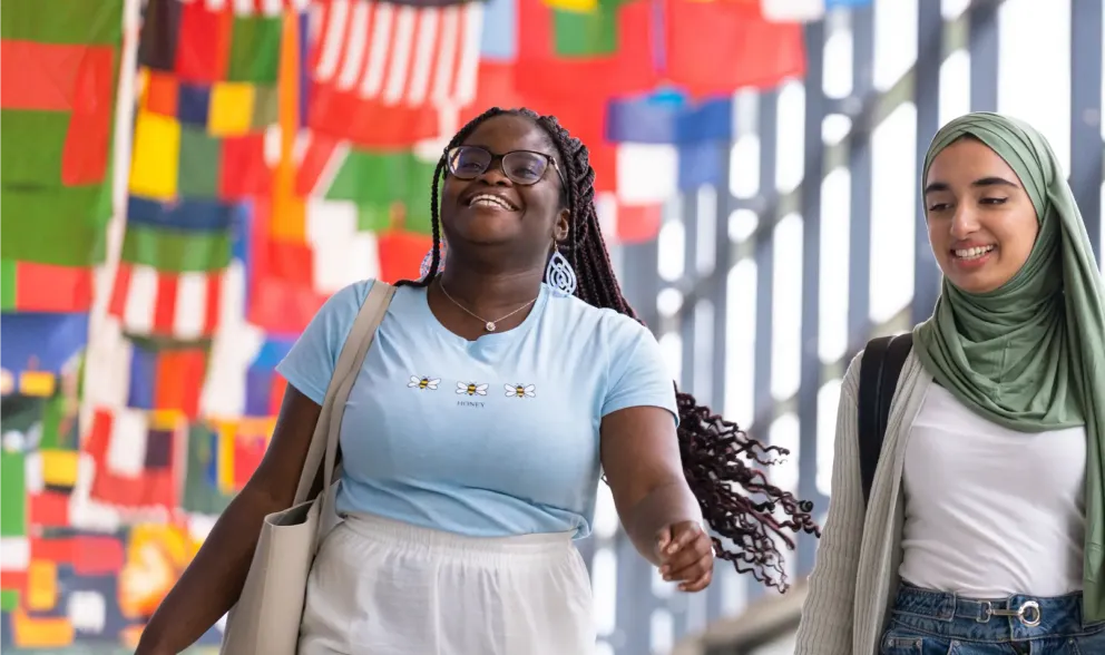 Two student smiling with flags behind them